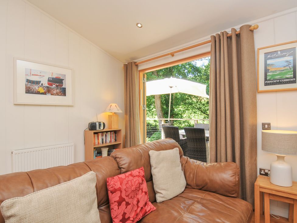 A living room with a sofa and bookshelves at 1 Stonerush Valley Liskeard