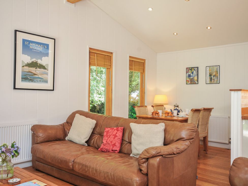 A living room with a sofa and a dining area at 1 Stonerush Valley in Liskeard