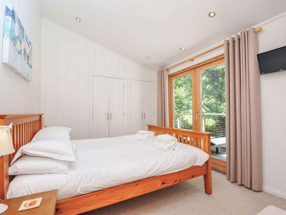 A bedroom with a bed and wooden closet at 1 Stonerush Valley Liskeard