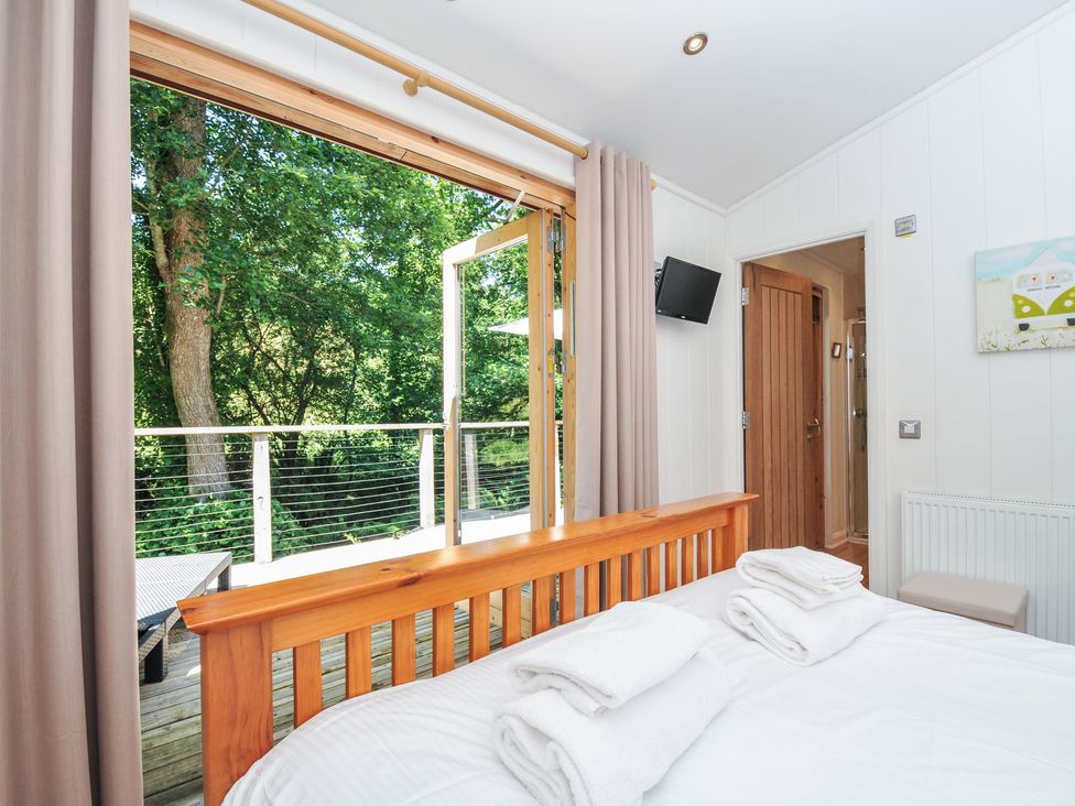 A bedroom with a bed and an open window at 1 Stonerush Valley Liskeard