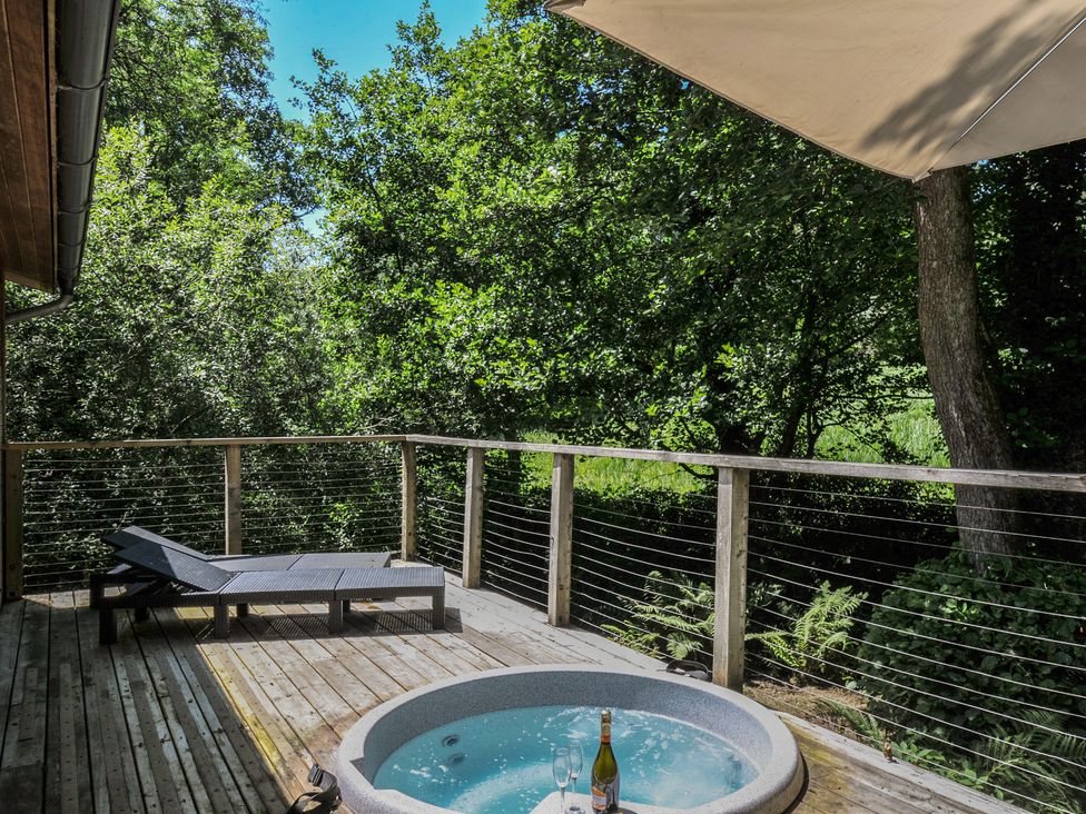 An outdoor deck area with a hot tub and lounge chair at 1 Stonerush Valley in Liskeard