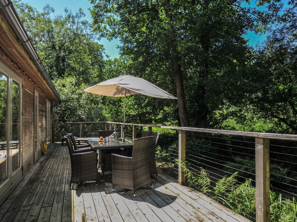 A deck with a table and chairs under an umbrella at 1 Stonerush Valley in Liskeard