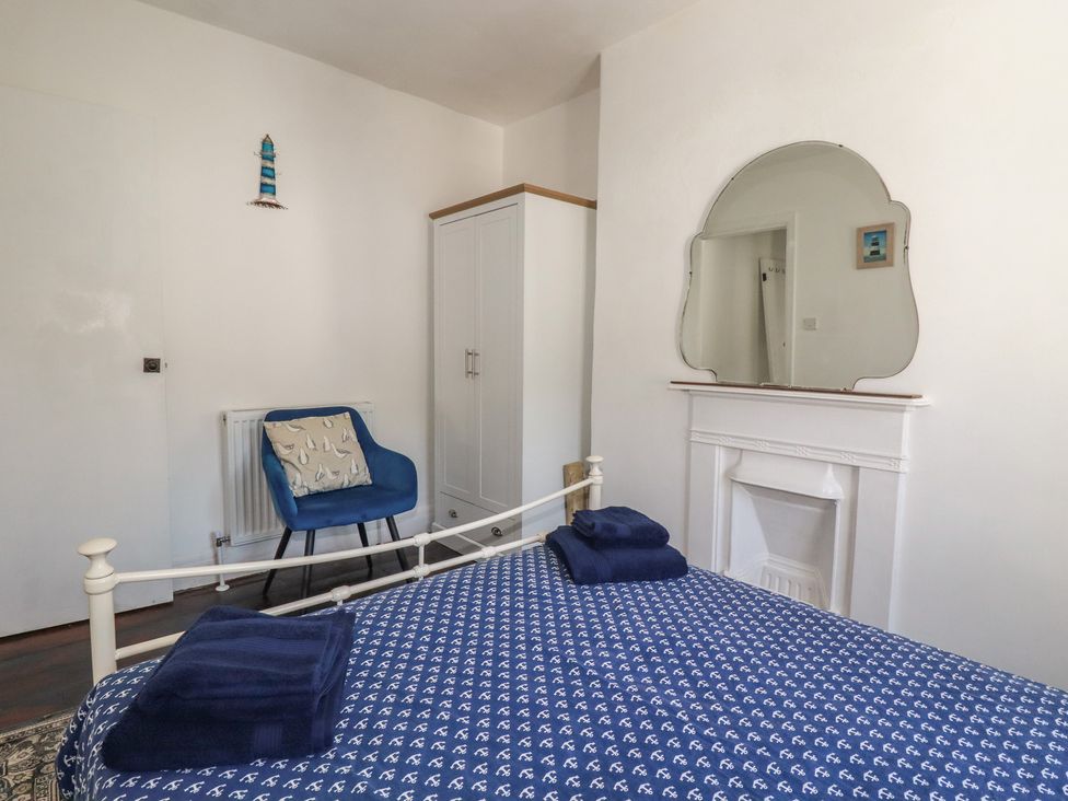 A bedroom with a bed and chair at Harbourside Retreat in Looe