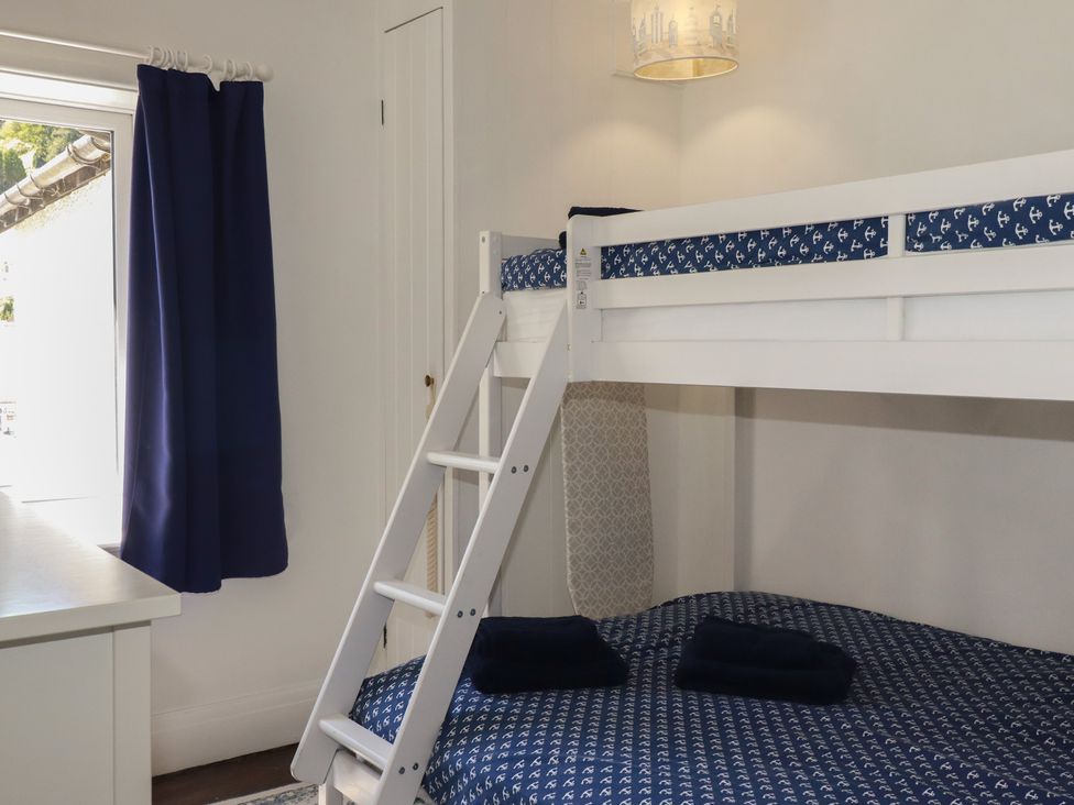 A bedroom with a bunk bed and window at Harbourside Retreat in Looe