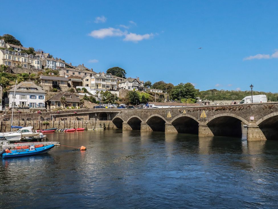 A bridge over a river with houses and boats at Harbourside Retreat in Looe