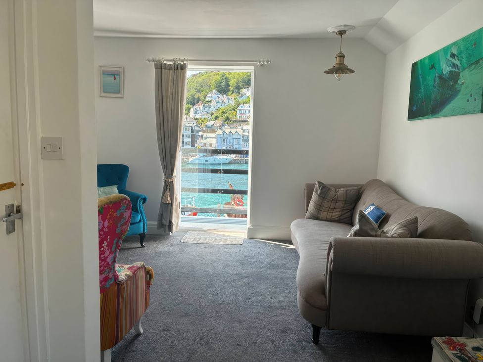 A living room with a sofa and armchair overlooking the harbor at Harbourside Retreat in Looe