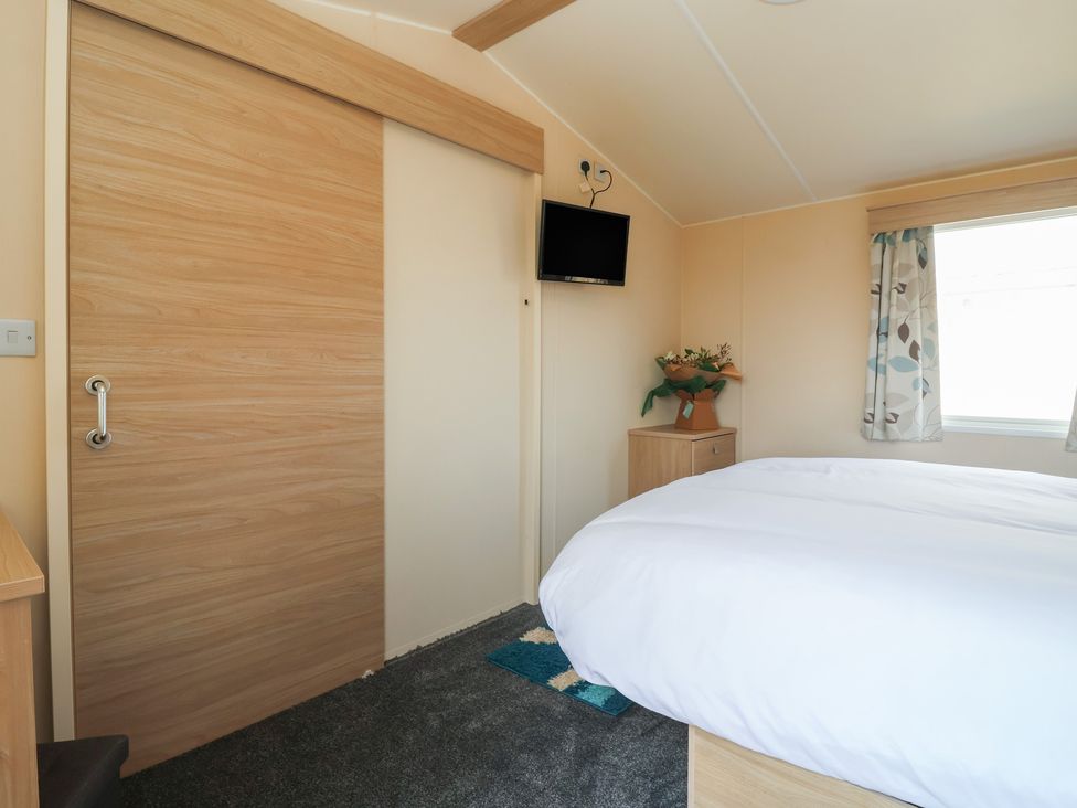 A bedroom with a bed and wall-mounted television at Paws and Relax