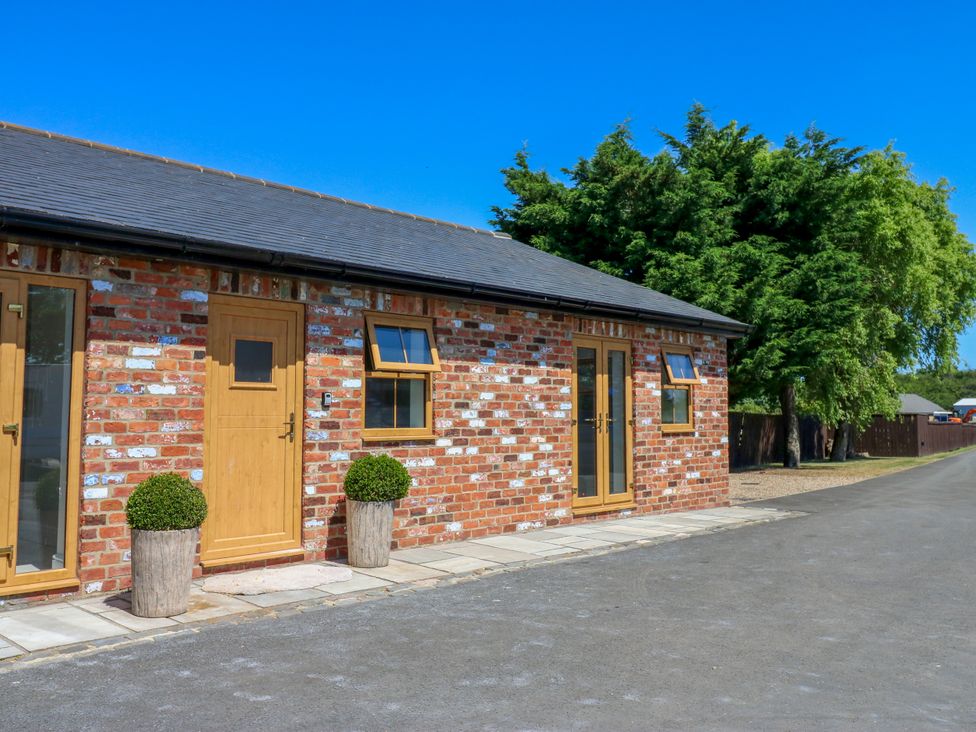 An exterior view of a cottage with a brick wall at Black Banks Farm Cottage in Darlington