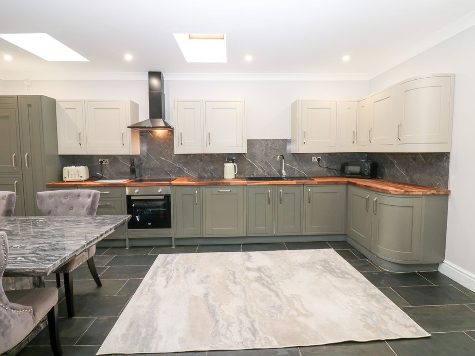 A kitchen with cabinets, oven, and dining table at Black Banks Farm Cottage in Darlington