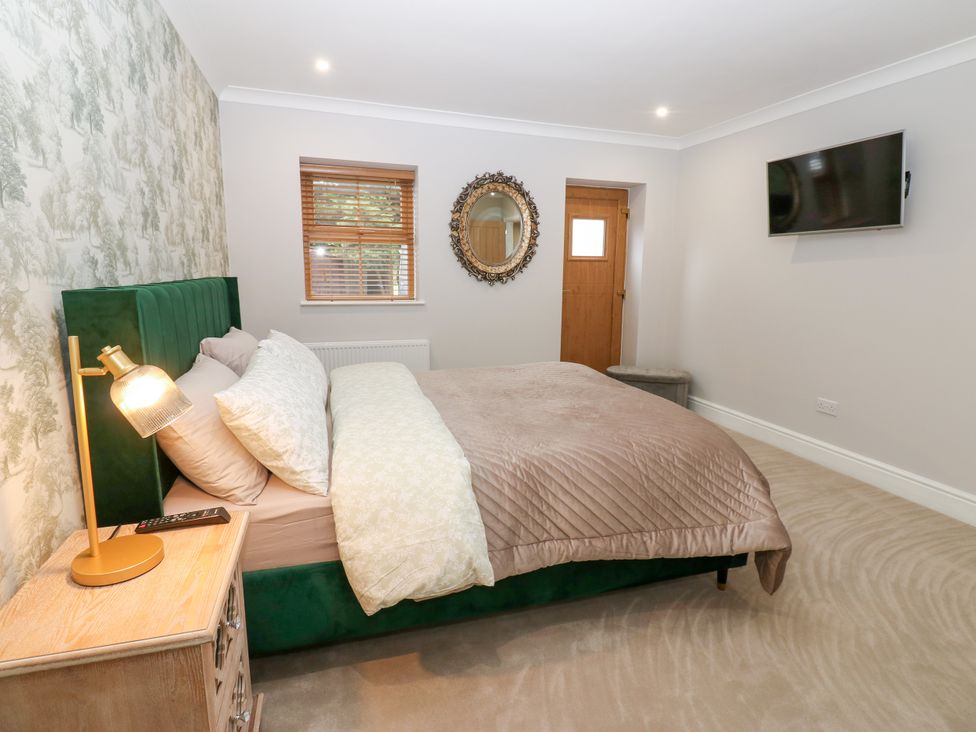 A bedroom with a bed, nightstand, and television at Black Banks Farm Cottage in Darlington