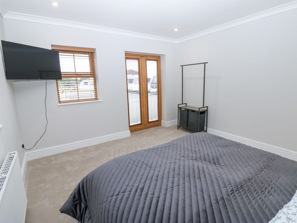 A bedroom with a television and double doors at Black Banks Farm Cottage in Darlington