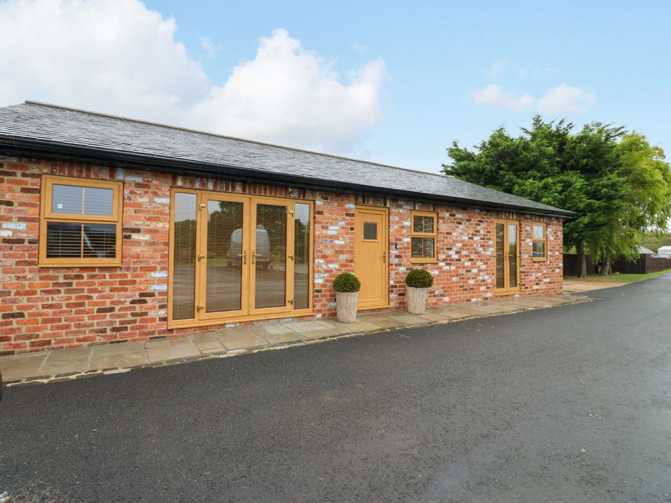An exterior view of a cottage with brick walls and wooden features at Black Banks Farm Cottage in Darlington