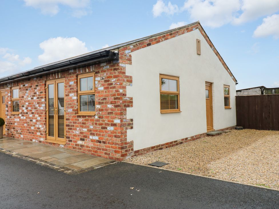 A brick exterior of a cottage with wooden door and gravel driveway at Black Banks Farm Cottage Darlington