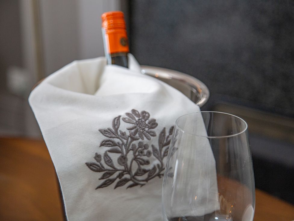 A wine bottle in an ice bucket with a napkin and a glass at Hudson House