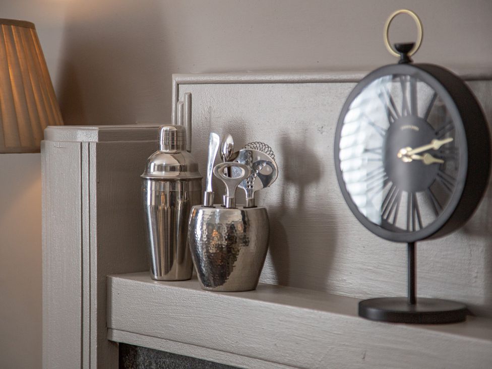 A shelf with a lamp, shaker, bar tools and a clock at Hudson House