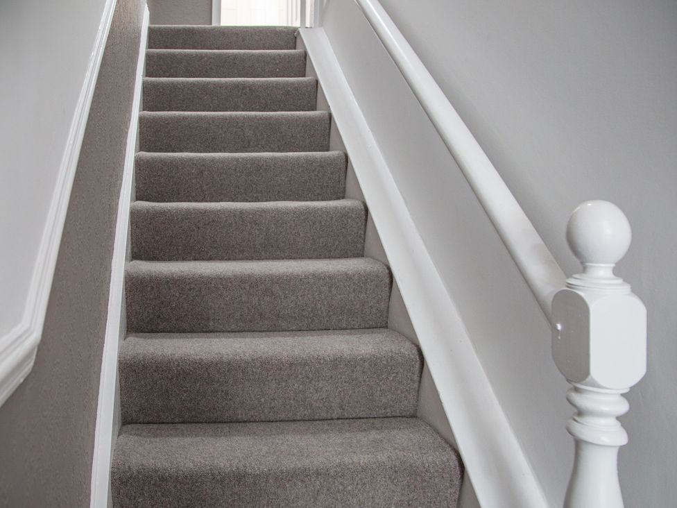 A staircase with carpet and a handrail at Hudson House