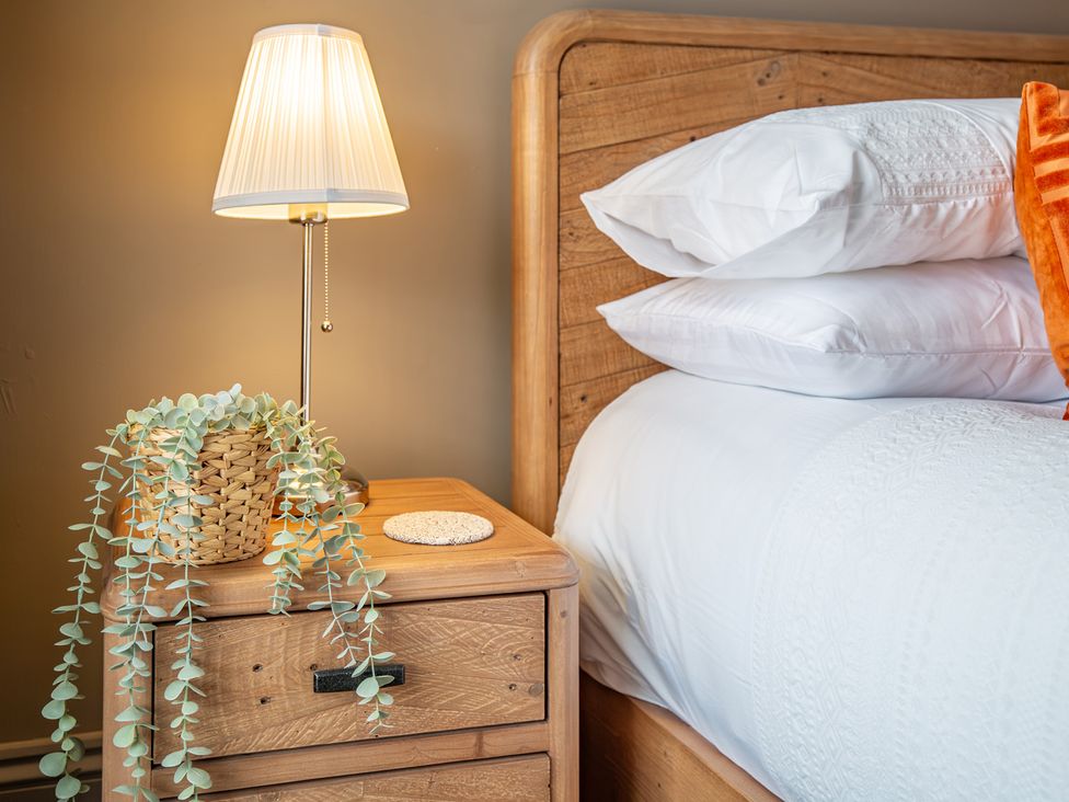 A bedside table with a lamp and a plant in a bedroom at Hudson House