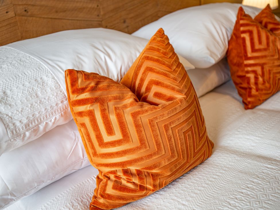 A bed with decorative orange pillows at Hudson House