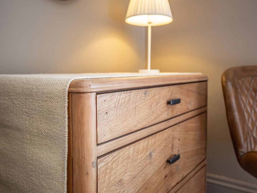 A wooden dresser with a lamp beside a chair at Hudson House 