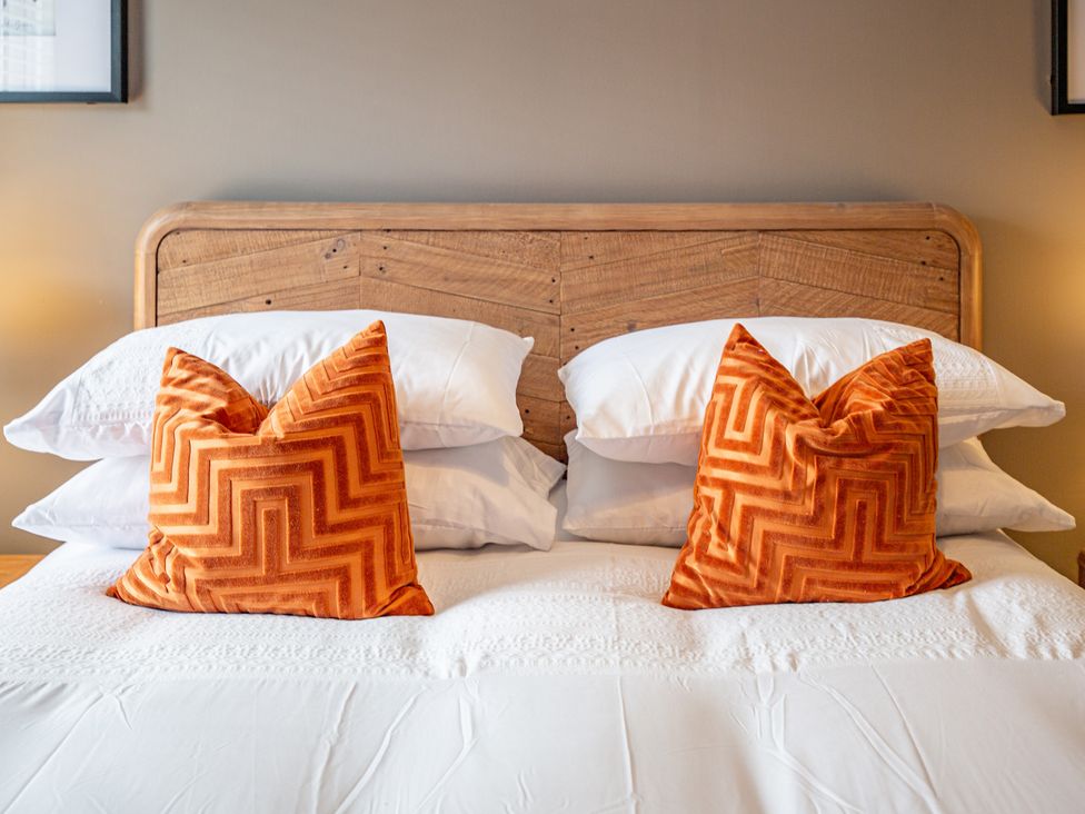 A bed with orange decorative pillows at Hudson House