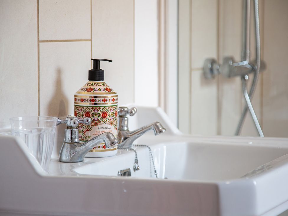 A bathroom sink with a soap dispenser and drinking glasses at Hudson House