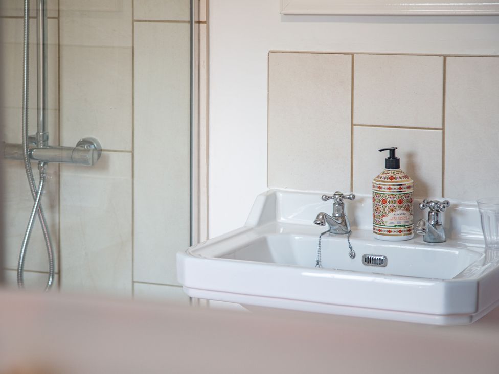 A sink with a soap dispenser and a shower in Hudson House