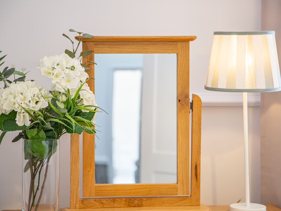 A mirror with a flower arrangement and a lamp at Hudson House