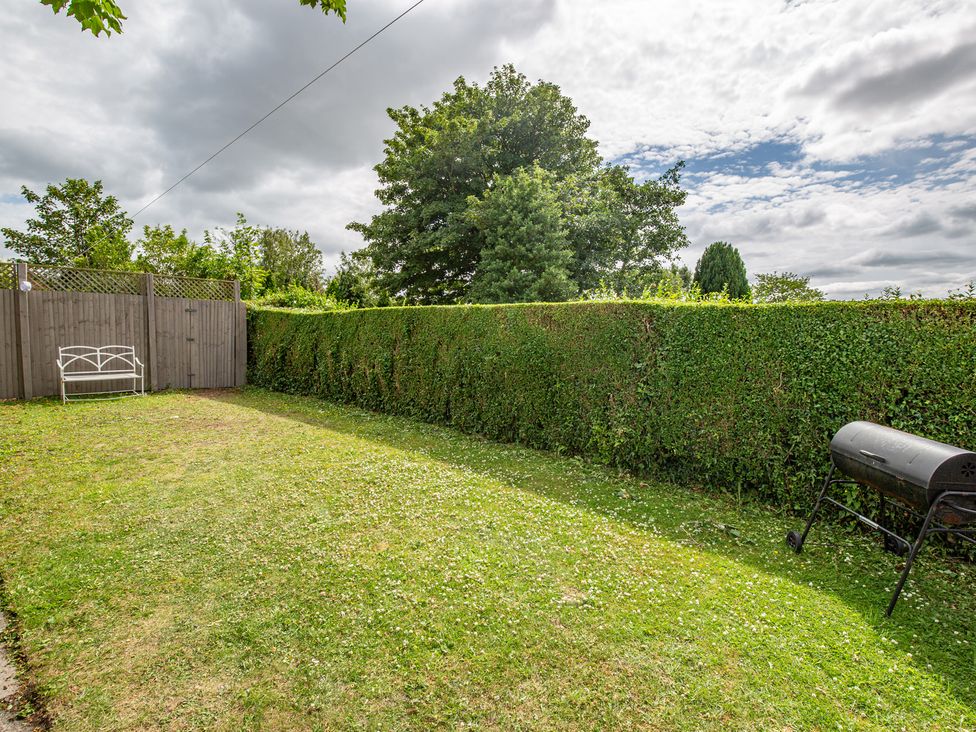 A garden with a hedge and bench at Hudson House