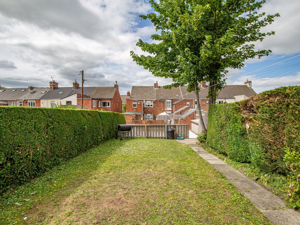 A garden with grass, hedges, and a tree at Hudson House