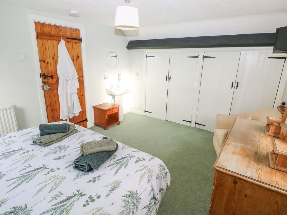 A bedroom with a bed and wooden furniture at Barn Cottage Haverfordwest