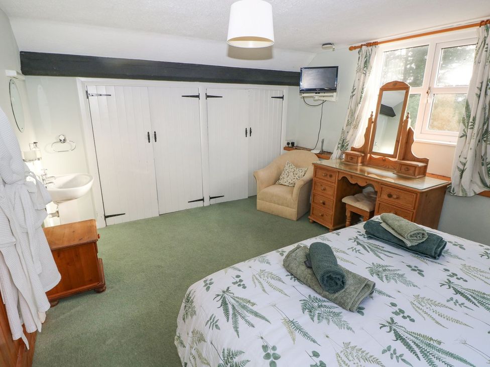 A bedroom with a bed, dresser, and sink at Barn Cottage in Haverfordwest