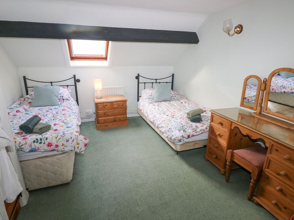 A bedroom with two beds and a dresser at Barn Cottage in Haverfordwest