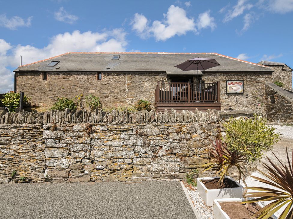 A stone building with a balcony and parasol at The Old Wagon House in Torpoint