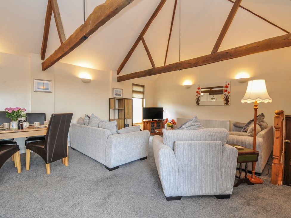 A living room with a table and chairs, a television, and sofas at The Old Wagon House in Torpoint