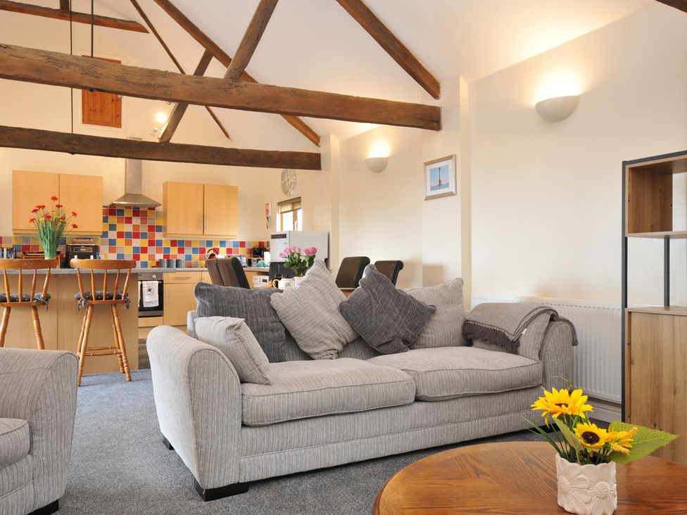 A living room with a sofa and kitchen area at The Old Wagon House in Torpoint