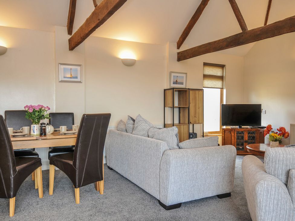 A living room with a sofa, dining table, and television at The Old Wagon House in Torpoint