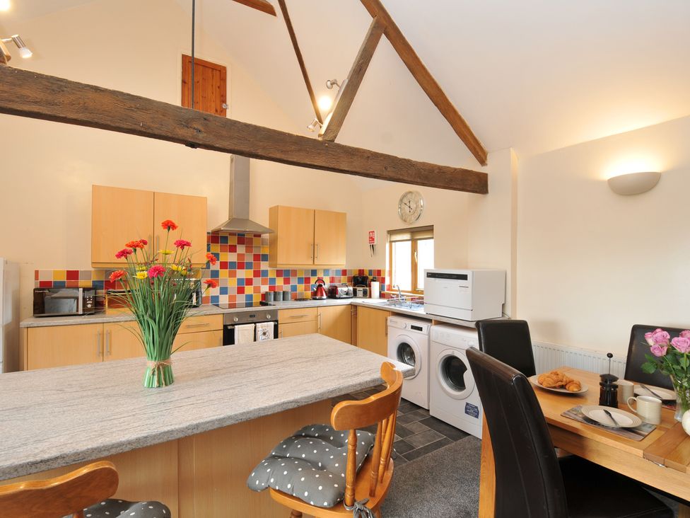 A kitchen with appliances and dining area at The Old Wagon House in Torpoint