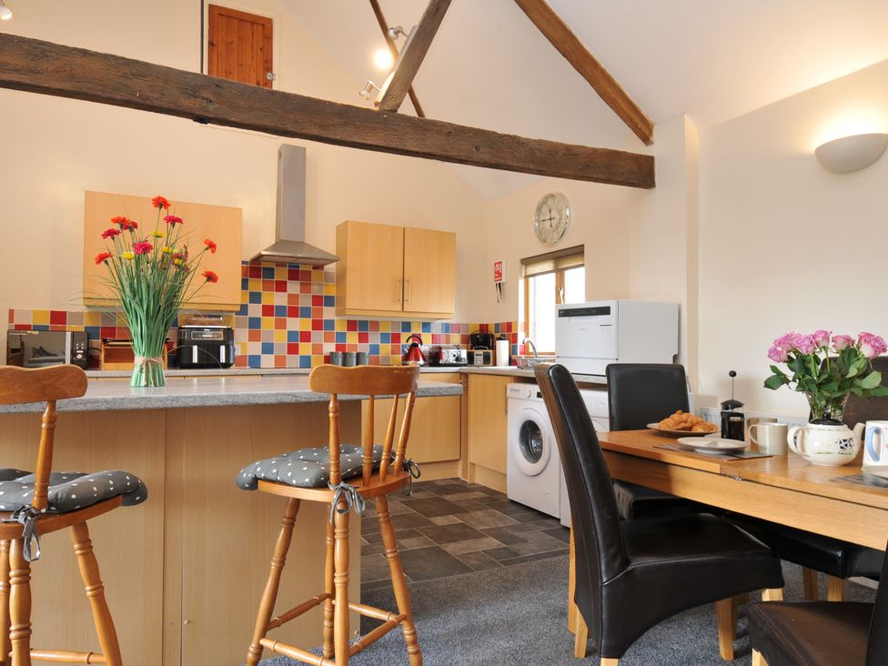 A kitchen with bar stools and dining table at The Old Wagon House in Torpoint