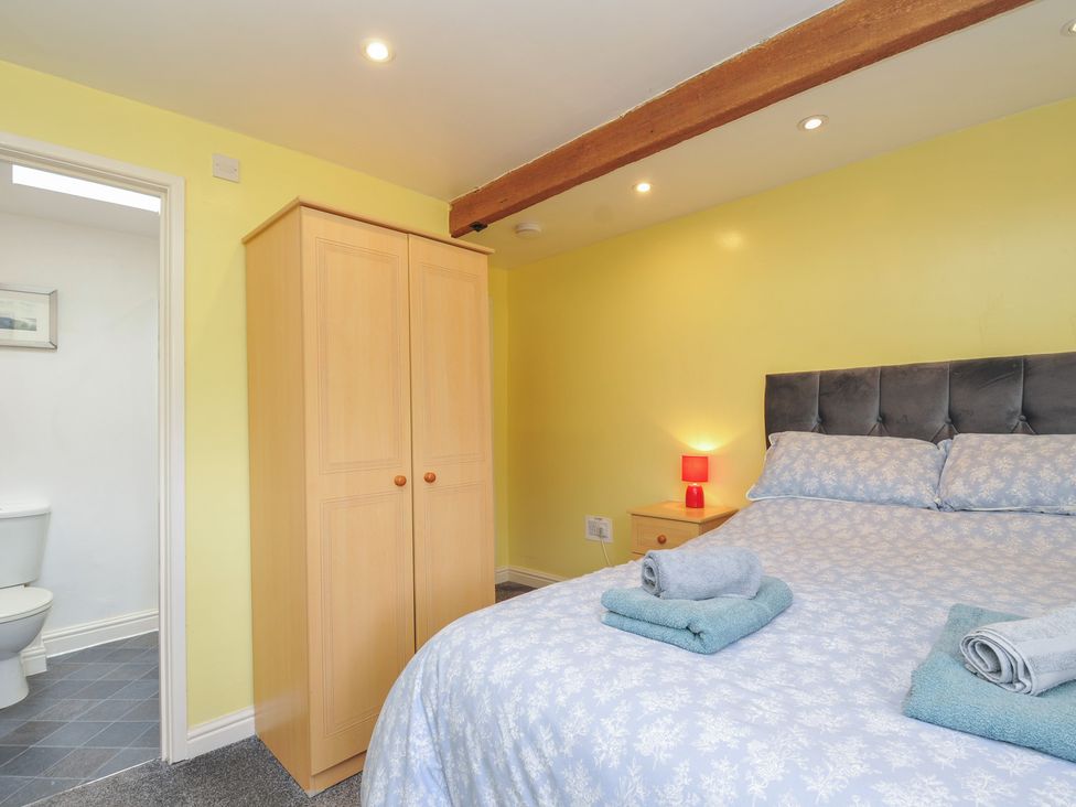 A bedroom with a bed and wardrobe at The Old Wagon House in Torpoint