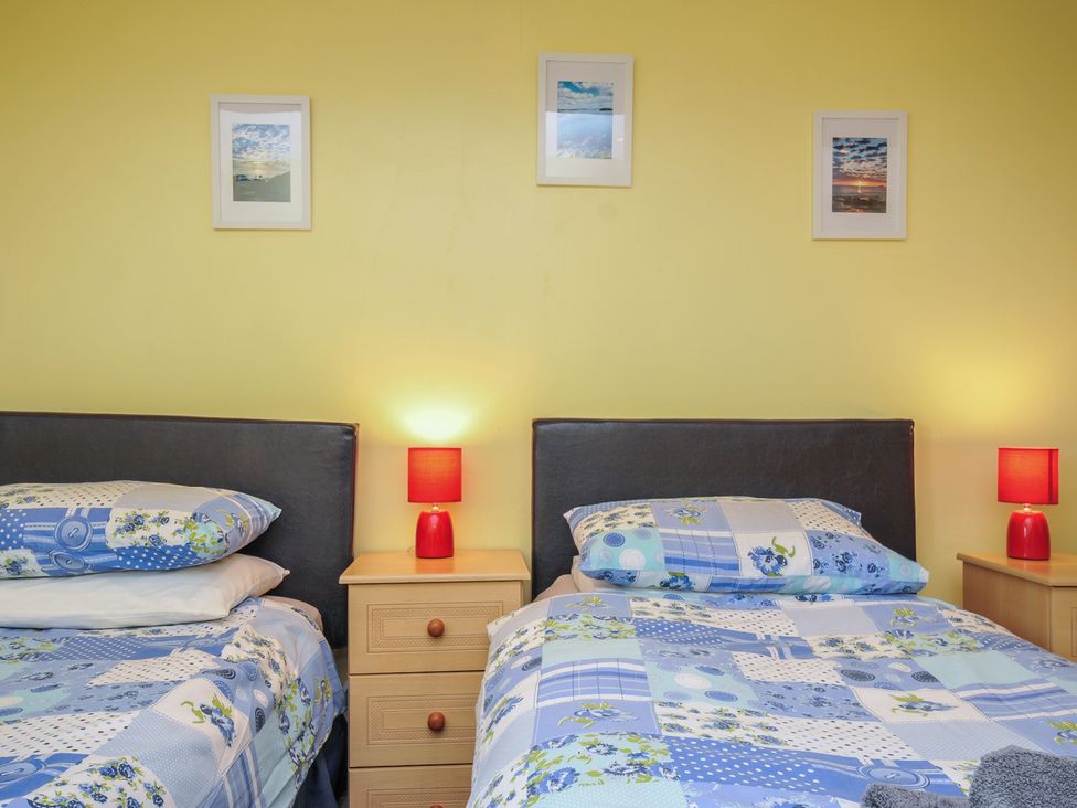 A bedroom with two beds and bedside tables at The Old Wagon House in Torpoint