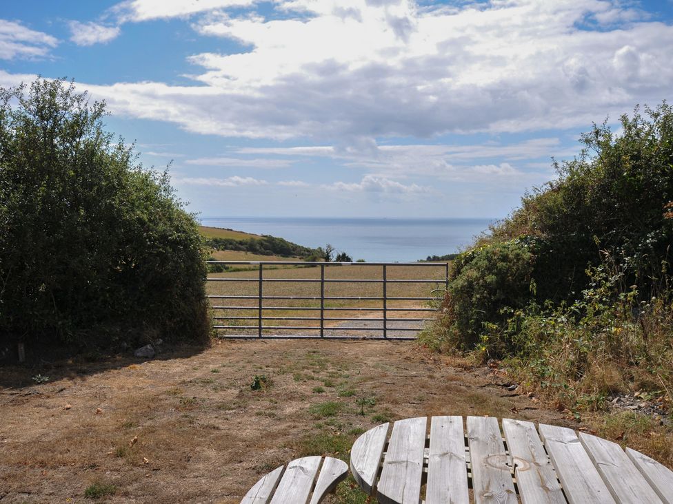 An outdoor view with a gate and table overlooking the sea at The Old Wagon House in Torpoint