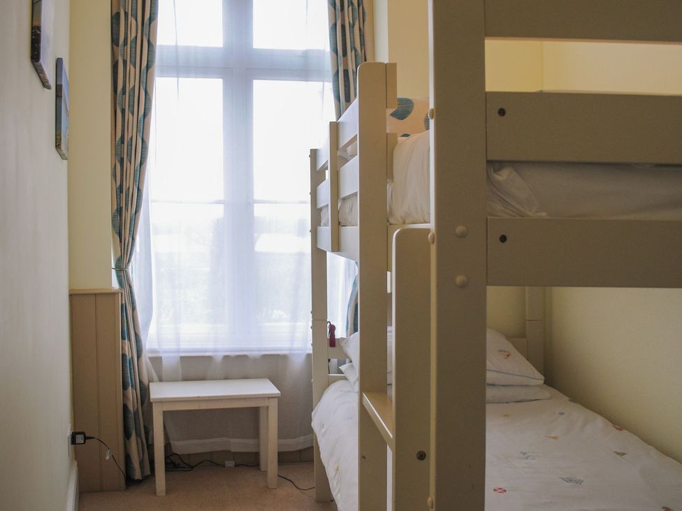A bedroom with a bunk bed and a side table at 4 The Salcombe in Salcombe