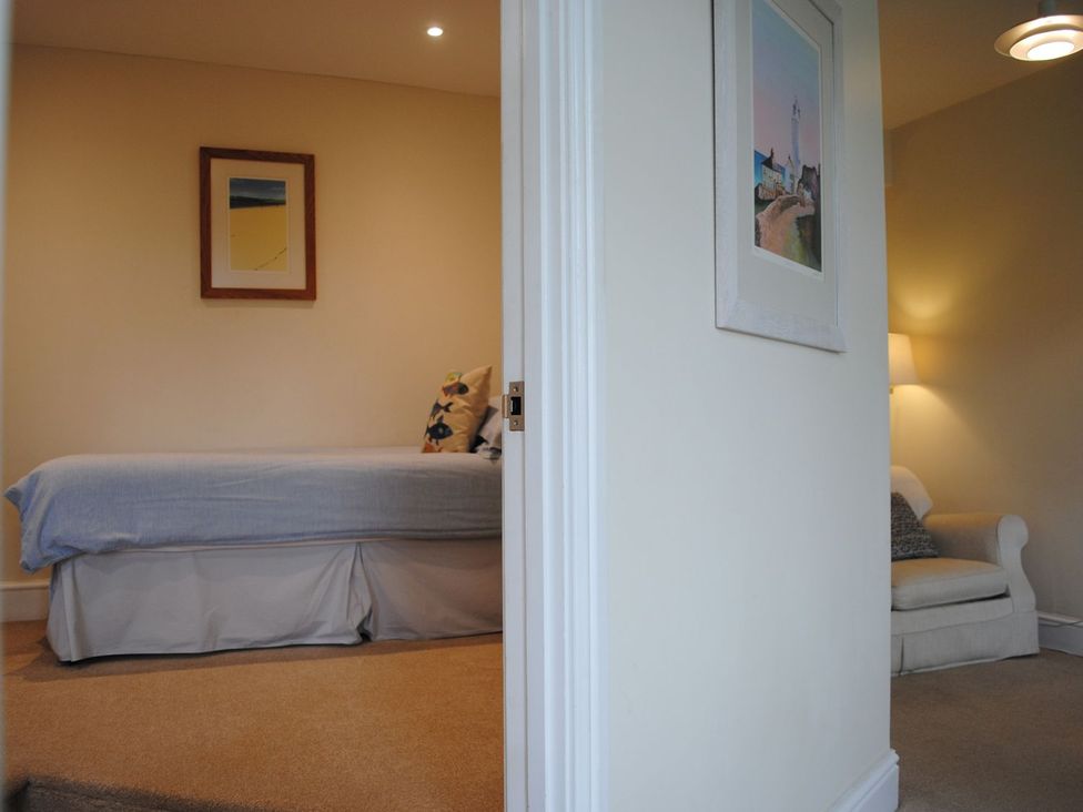 A bedroom with a bed and a chair at 4 The Salcombe, Salcombe