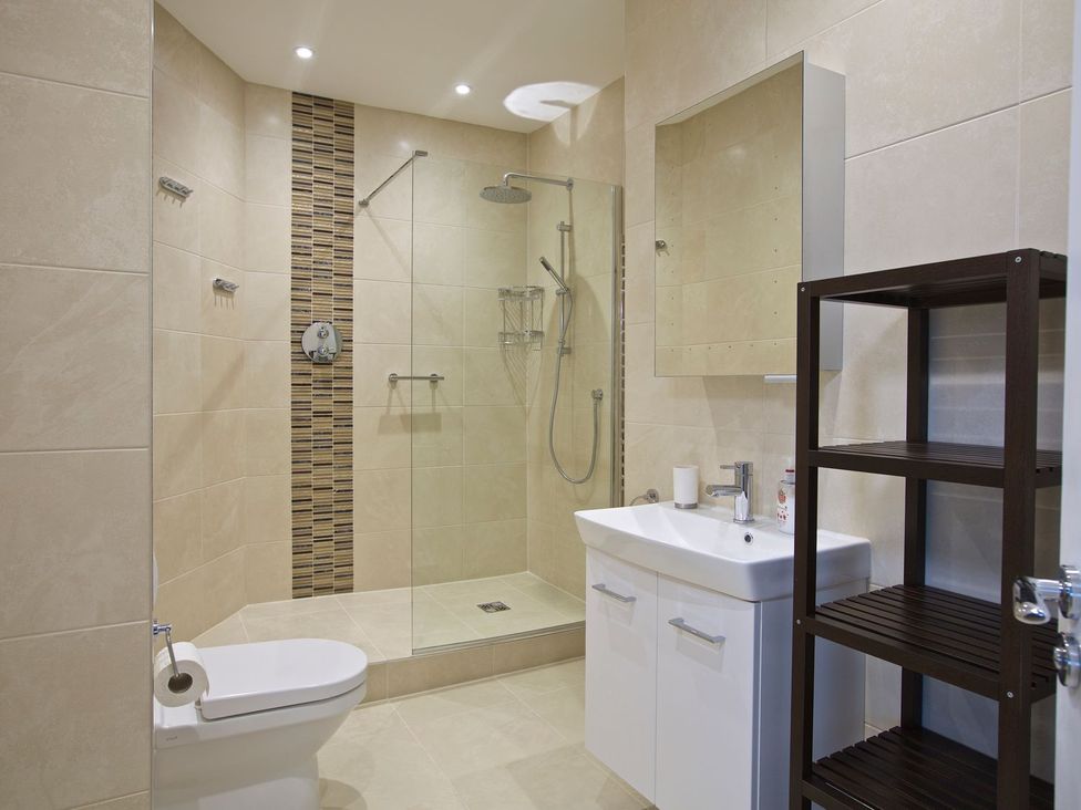 A bathroom featuring a shower, toilet, and sink with a mirror at 4 The Salcombe in Salcombe