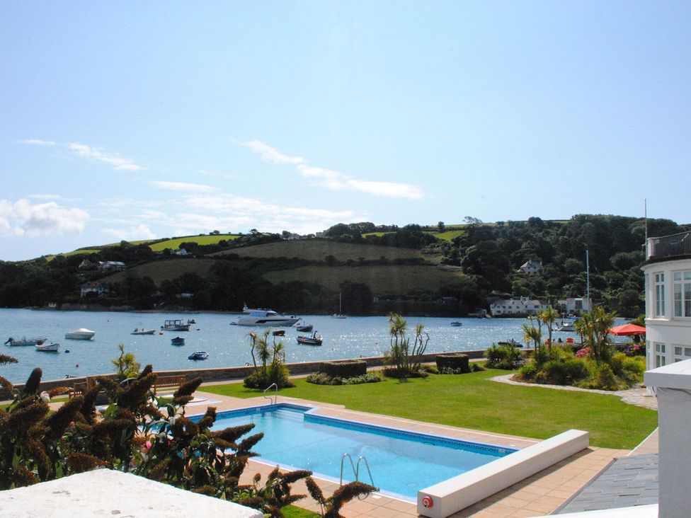 A pool with grass and boats by the water at 4 The Salcombe in Salcombe