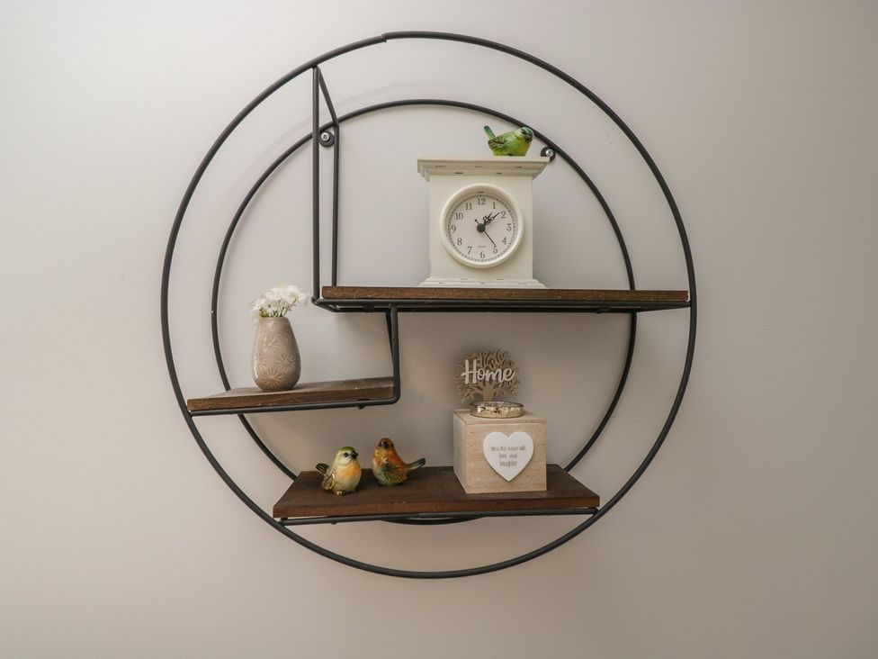A wall shelf with decorative items and a clock at The Laurels in Wimborne Minster
