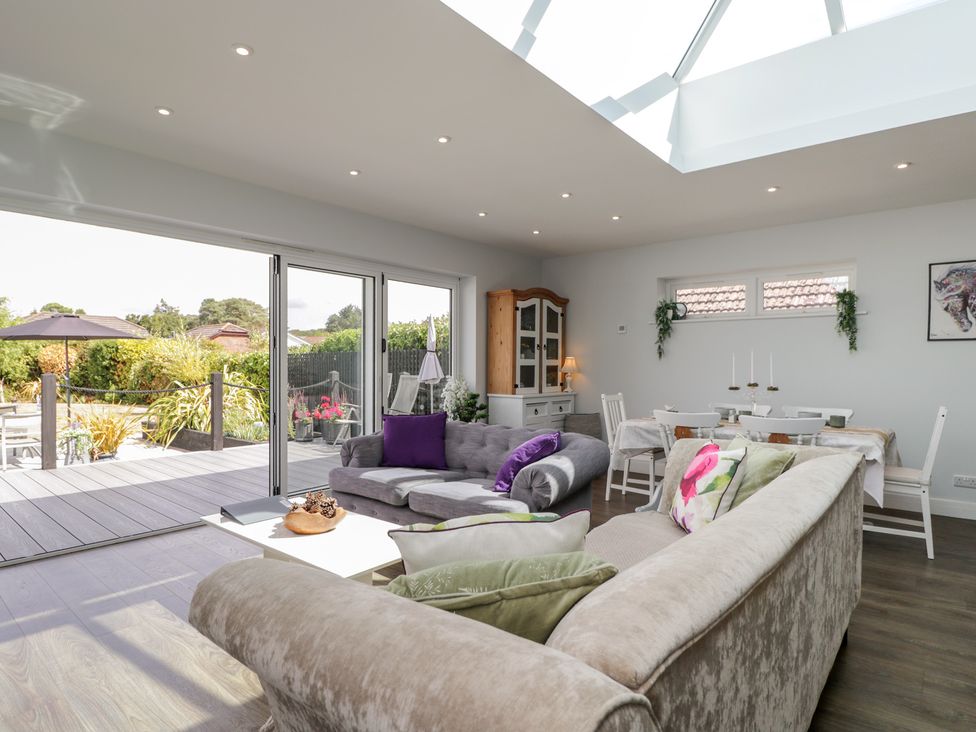 A living room with a sofa and a dining area at The Laurels in Wimborne Minster