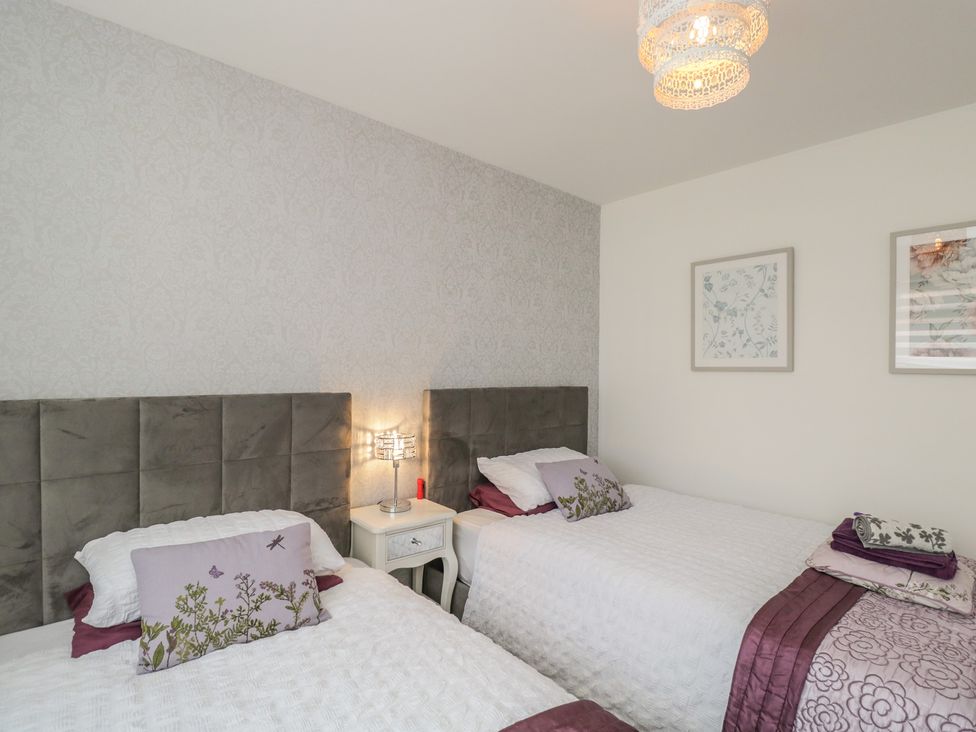 A bedroom with two beds and a bedside table at The Laurels in Wimborne Minster