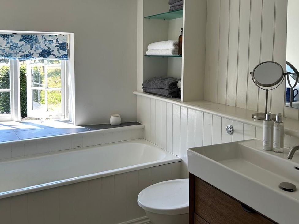 A bathroom with a bathtub, sink, and shelf at French Mill in Shaftesbury