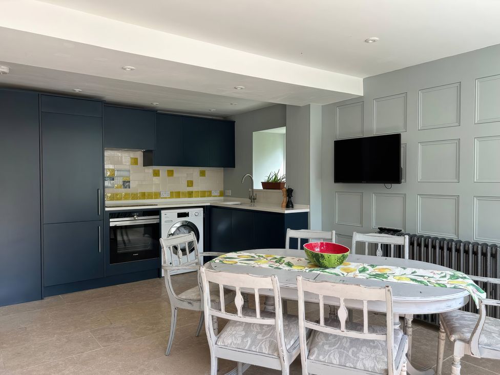 A kitchen with cabinets, a dining table, and a television at French Mill in Shaftesbury
